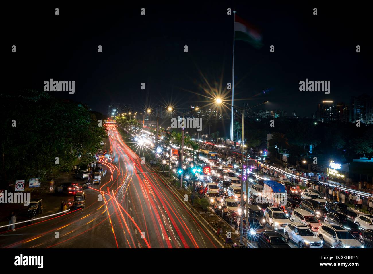 Navi Mumbai, Indien – 15. August 2023 leichte Autospuren bei Nacht auf Palmenstrandstraße in Navi Mumbai, Indien mit indischer Flagge im Hintergrund Stockfoto