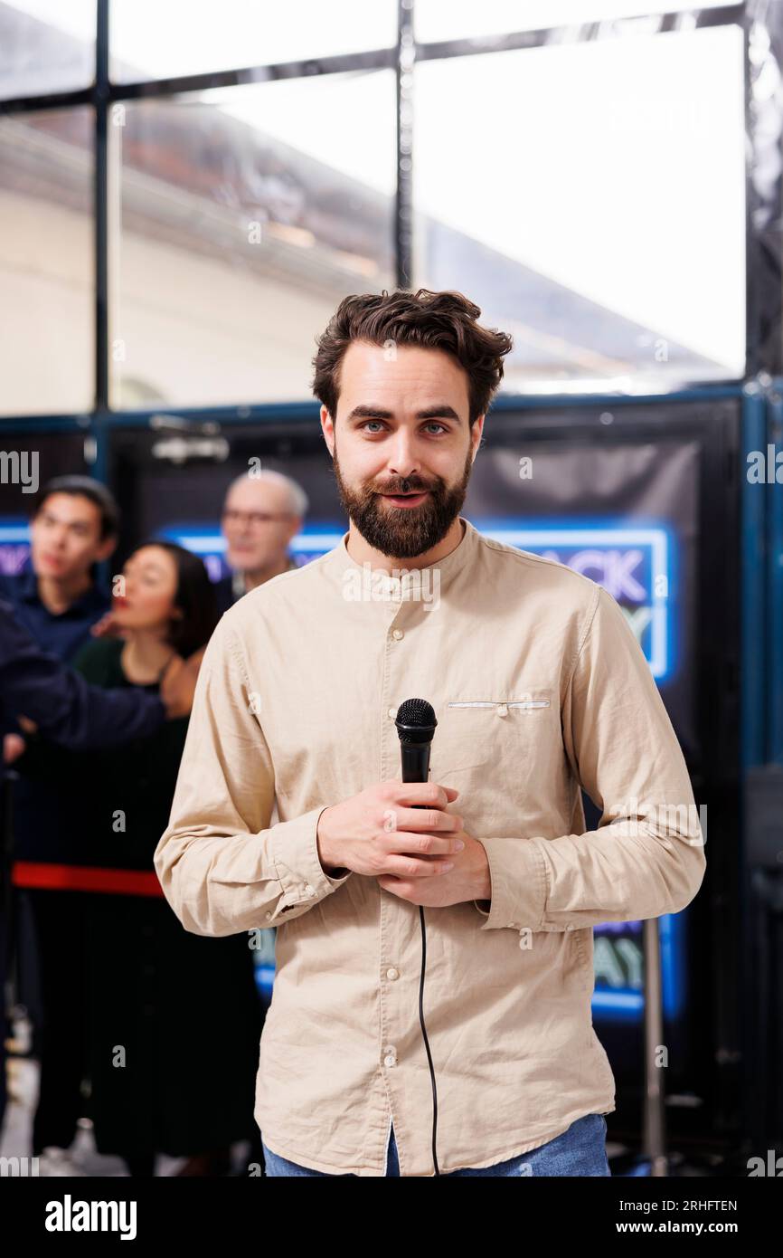 TV-Journalist mit Reportermikrofon, der mit der Kamera spricht und von der Black Friday-Verkaufsveranstaltung im Einkaufszentrum sendet. Korrespondent spricht über die geschäftige Weihnachtseinkaufszeit für die Nachrichtensendung Stockfoto