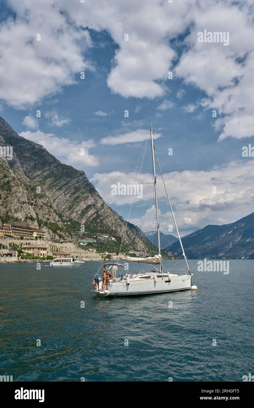 Segelboot mit Besatzung vor der Küste von Limone Sul Garda am Westufer des Gardasees, Lago di Garda in Italien Stockfoto