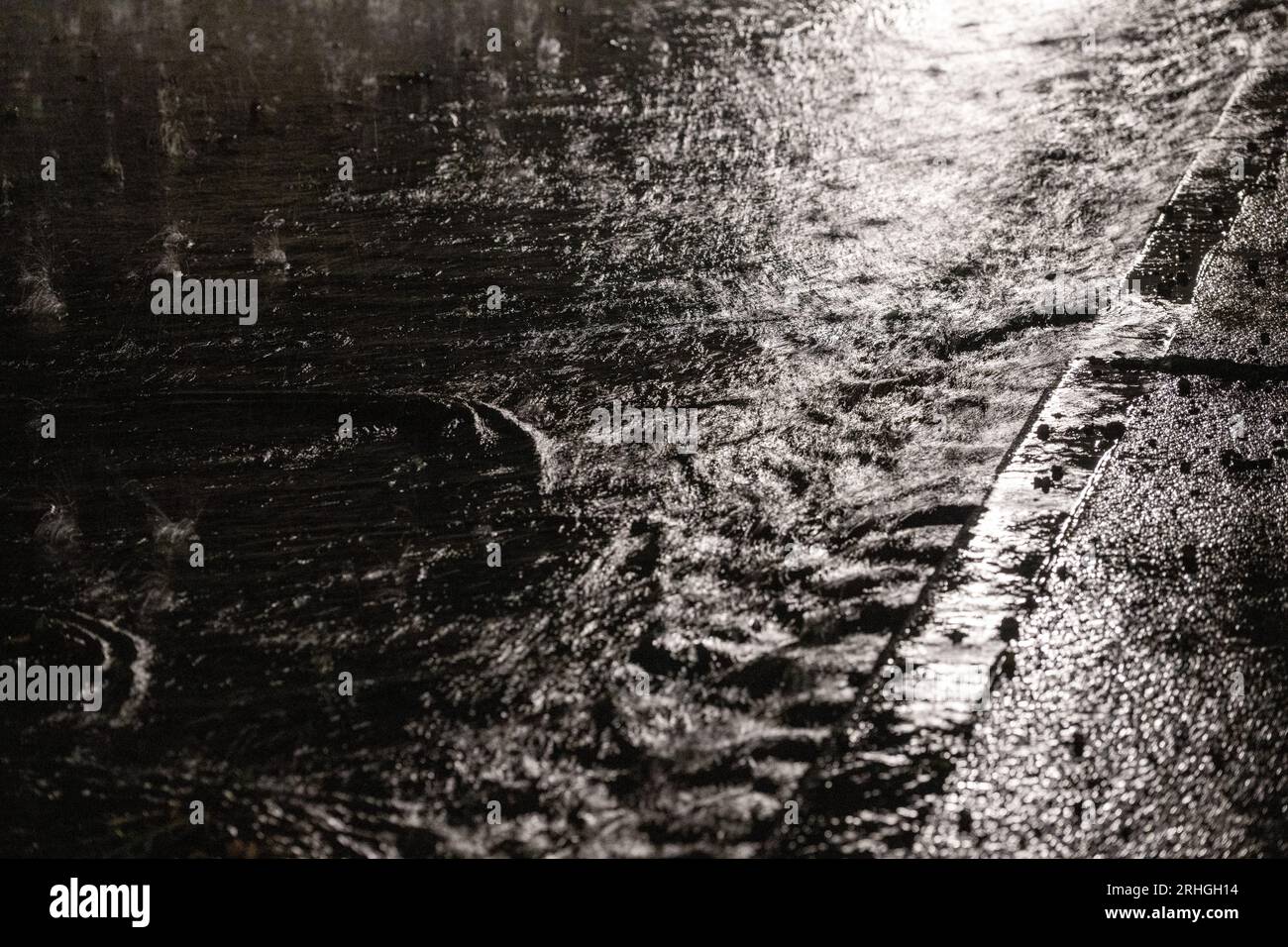 Heldburg, Deutschland. Aug. 2023. Regen läuft entlang der Bordsteinkante. In Heldburg (Thüringen) war die Kanalisation zeitweise nicht in der Lage, die Wassermassen aufzunehmen. Quelle: Pia Bayer/dpa/Alamy Live News Stockfoto