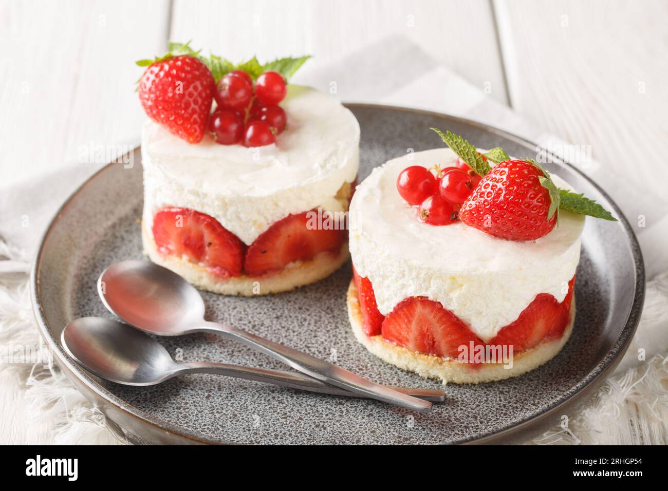 Französische Erdbeeren-Fraisier-Minikuchen auf dem Teller auf dem Tisch. Horizontal Stockfoto