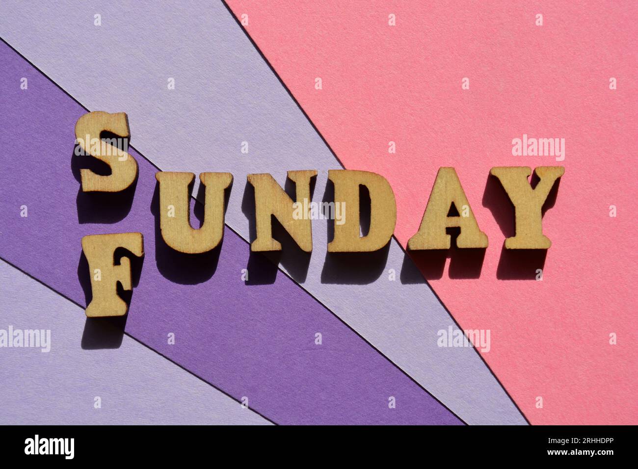 Sonntag, Funday, Wörter in Holzbuchstaben isoliert auf lila und rosa Hintergrund als Banner-Überschrift Stockfoto
