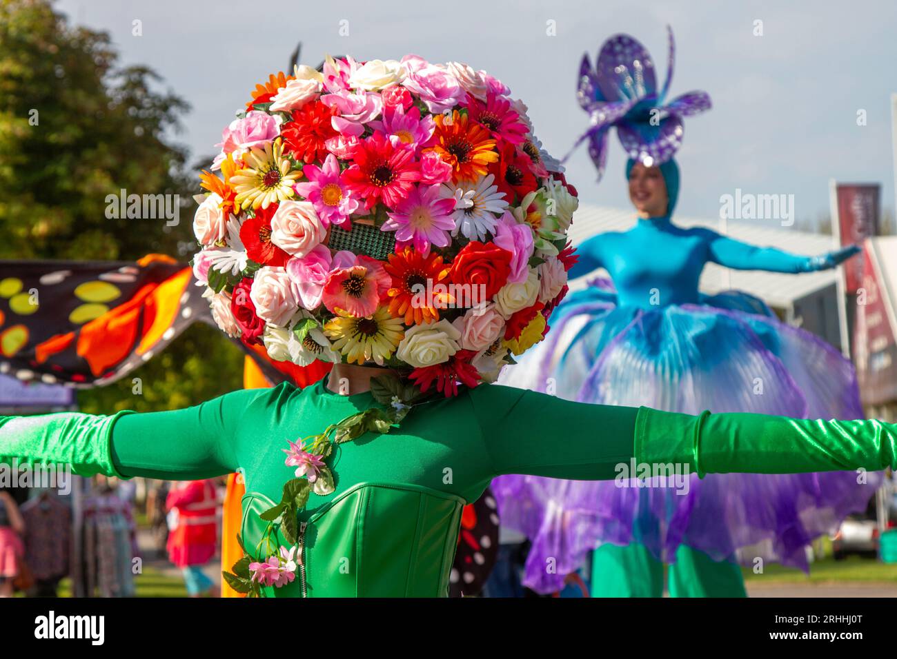 Ein Begrüßer mit einem floralen Kopfschmuck, der mit Blumen verziert ist. Ein helles und farbenfrohes Festival 2023 im Nordwesten Besucher werden von Blumenpfahlwanderern begrüßt, wenn sie an den vier Tagen der beeindruckenden Blumenausstellung ankommen. Southport Merseyside, Großbritannien Stockfoto