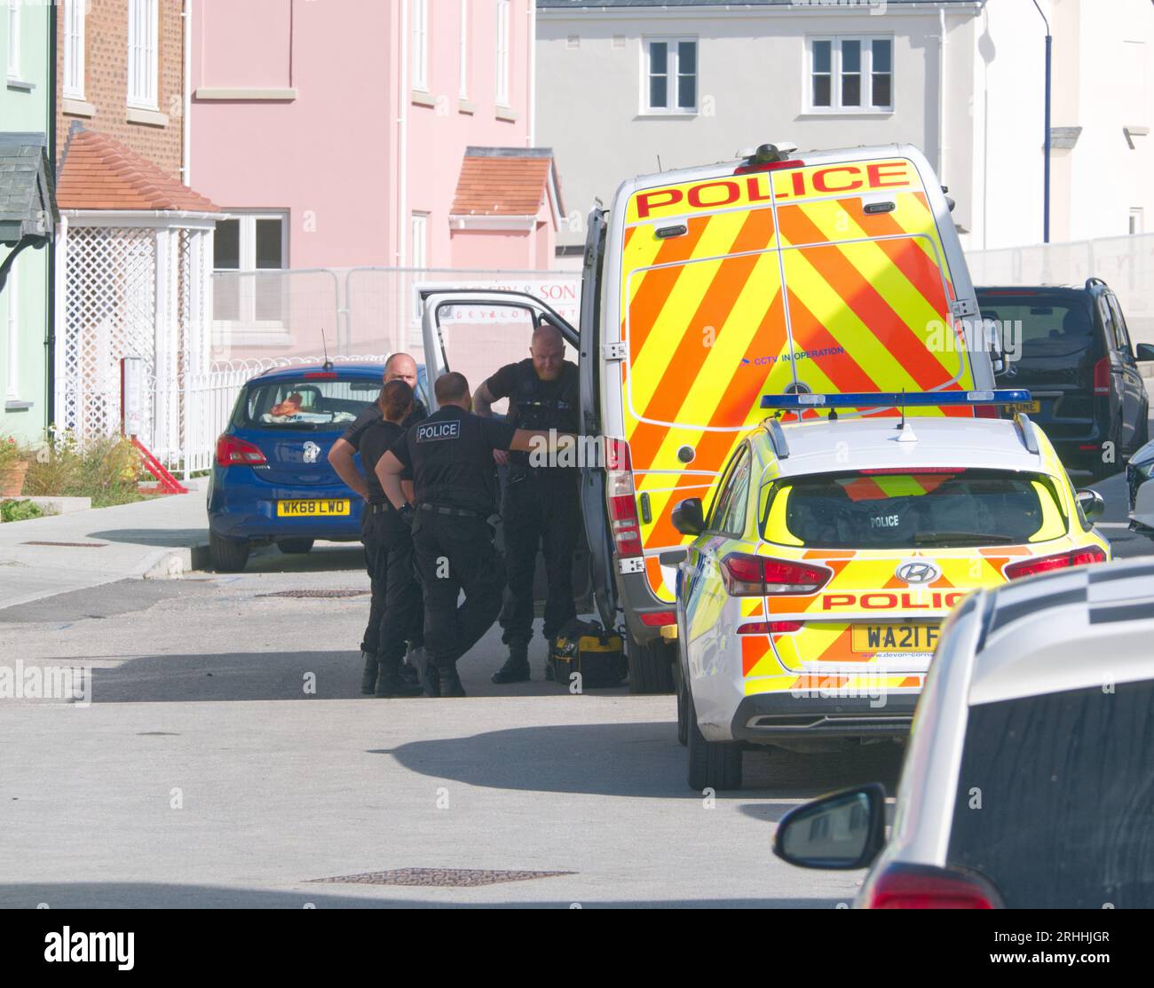 Mehrere Polizeibeamte, die von einem Schnüffelhund begleitet werden, werden bei einem zwangsweisen Zutritt zu einem Haus in der Straße Kosti Veur Woles beobachtet. Dieser Ort befindet sich im Modelldorf des King Charles Projekts am Stadtrand von Newquay. Ein Augenzeuge berichtete, dass die Eingangstür kaputt war, um Zugang zu erhalten. Mehrere Personen wurden von Polizisten begleitet. Devon und Cornwall Polizei machen eine Drogenattacke. Nansledan Cornwall Großbritannien. August 2023. Robert Taylor Stockfoto