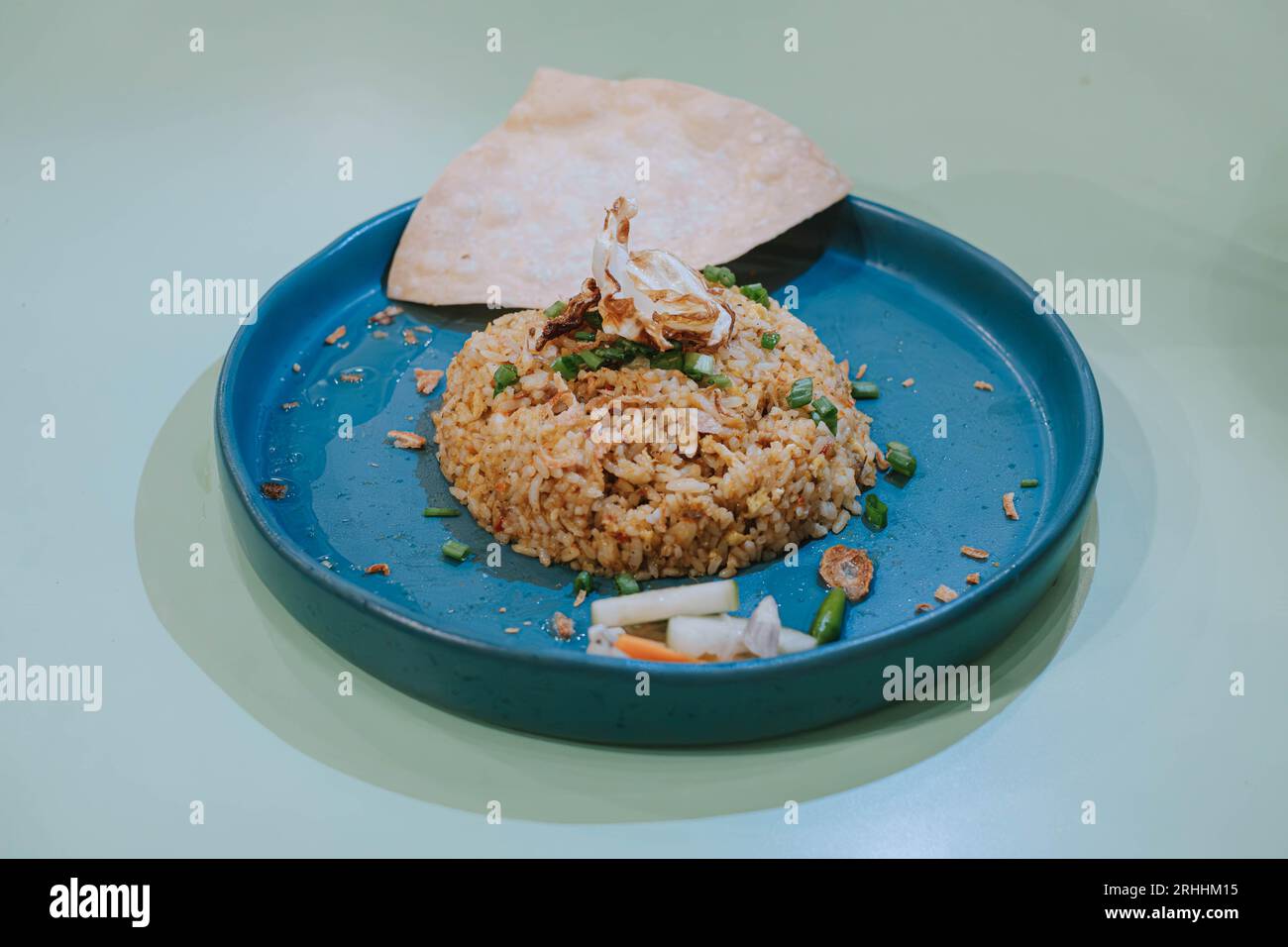 Selektiver Schuss einer Platte Nasi Goreng oder gebratener Reis mit Cracker, Karotten und Gurke auf isoliertem Salbeigrün-Pastellhintergrund Stockfoto