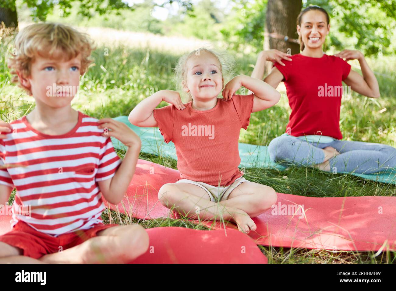 Glückliche Familienausübung, während Sie im Park auf der Matte sitzen Stockfoto