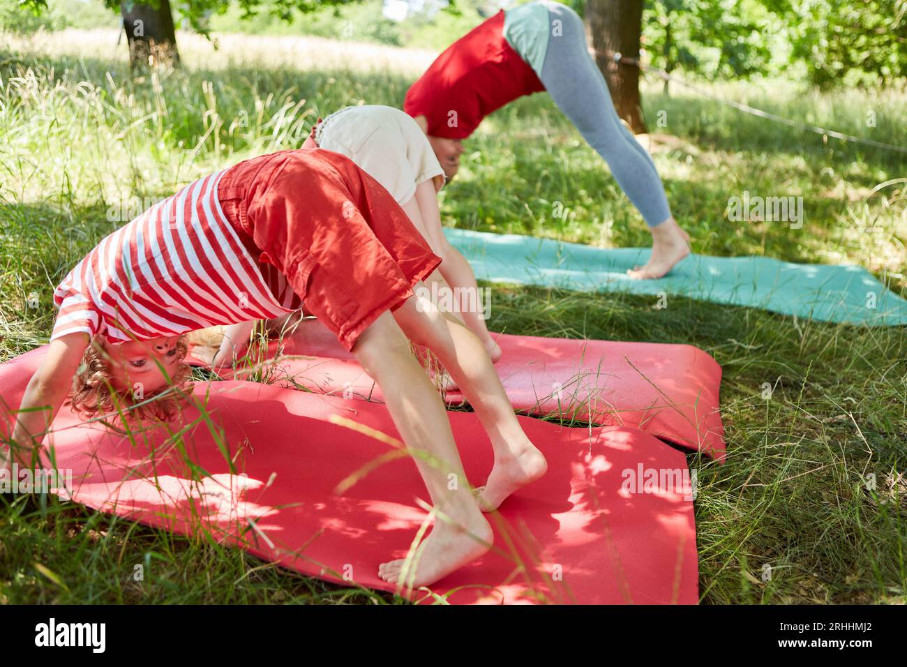 Sohn und Tochter machen Dehnübungen mit Mutter auf Yogamatte im Garten Stockfoto