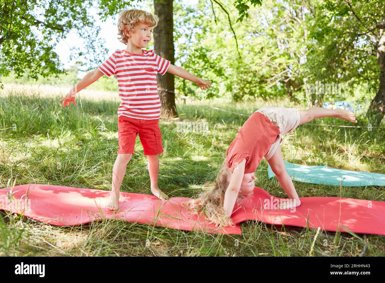Bruder und Schwester spielen zusammen auf Yogamatten im Garten Stockfoto