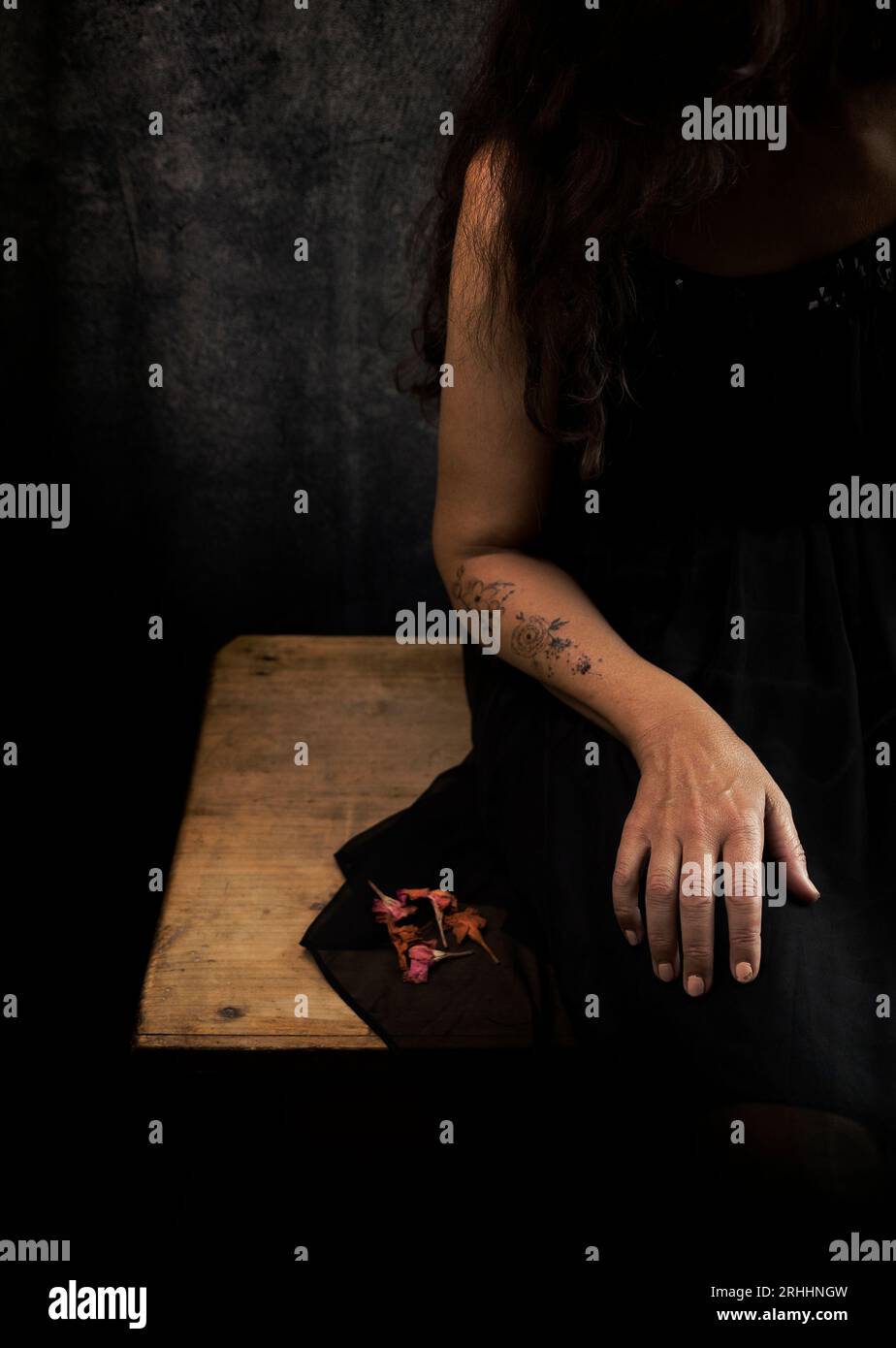 Frau in schwarzem Kleid mit getrockneten Blumen in der Hand V Stockfoto