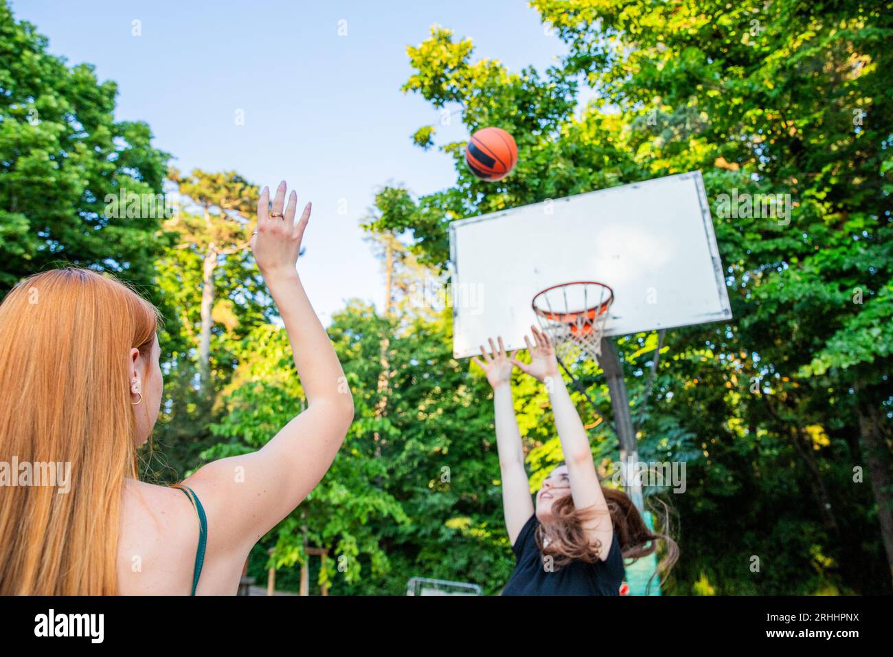 Ein Basketballspieler schießt den Ball in Richtung des Korbs, während sein Gegner verteidigt Stockfoto