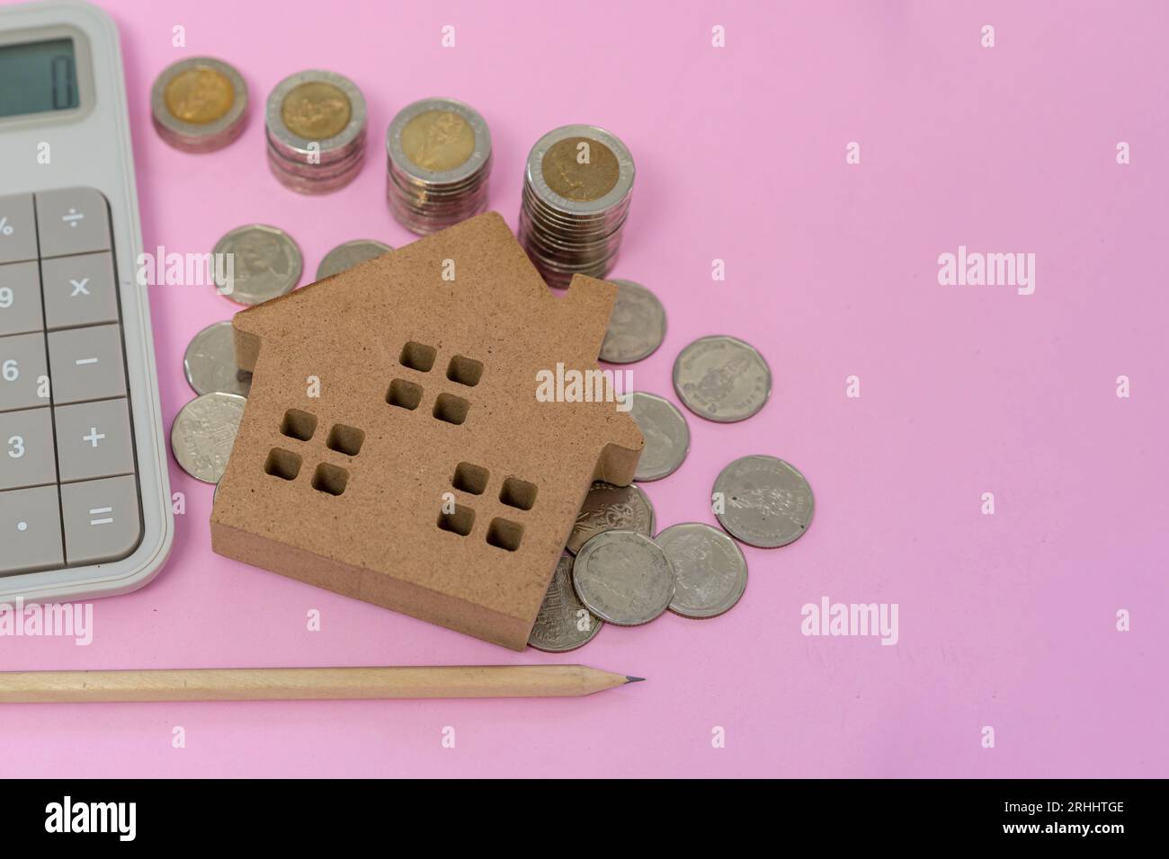 Geldmünzen und Taschenrechner auf pastellrosa Hintergrund Stockfoto