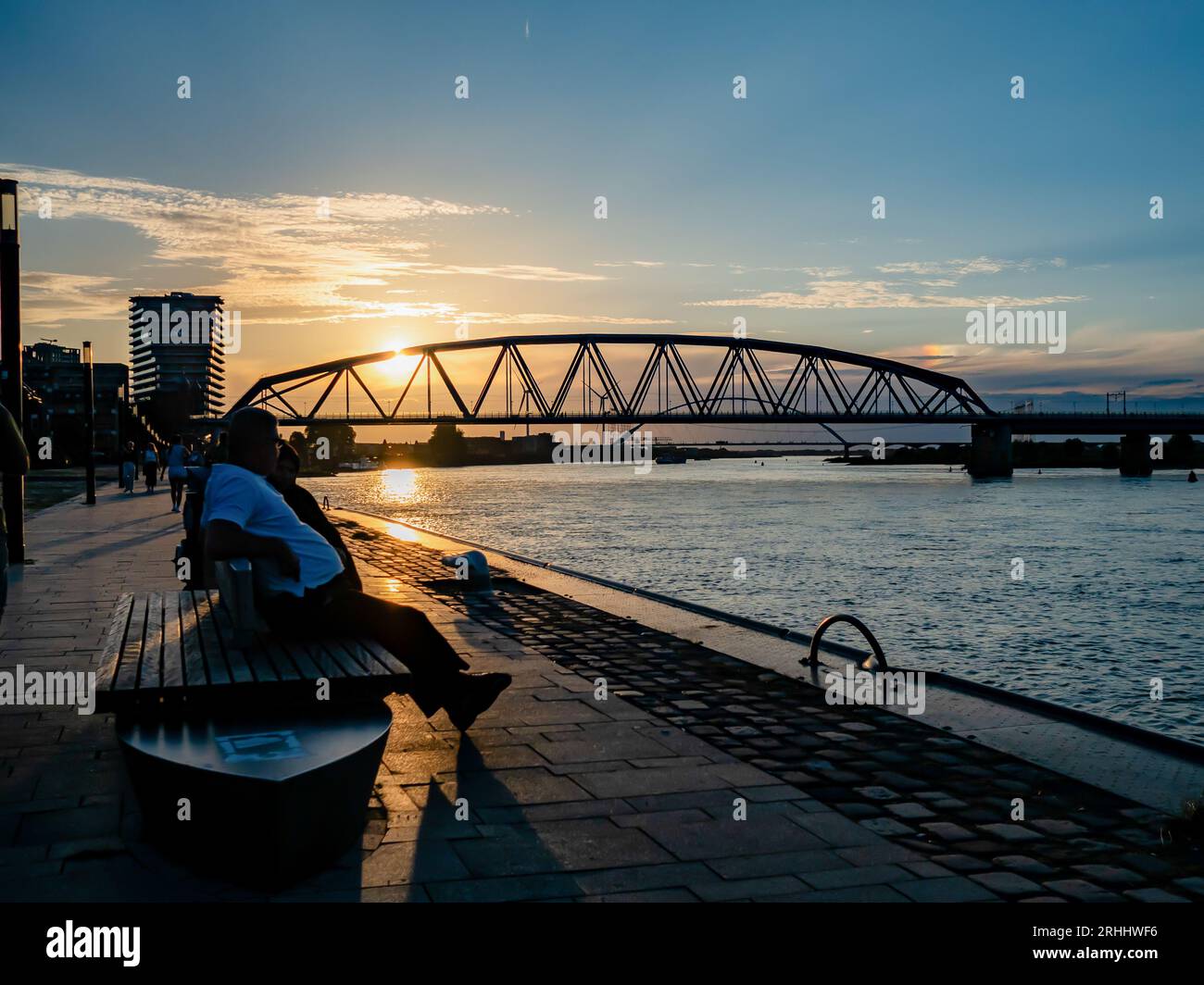 Nijmegen, Gelderland, Niederlande. August 2023. Ein Mann sitzt in der Nähe des Wall River während des Sonnenuntergangs. Nach einigen wechselhaften Wochen können sich die Niederlande auf das Sommerwetter in dieser Woche freuen. Die Temperaturen sind gestiegen und es gibt viel Platz für Sonnenschein. In den folgenden Tagen bleibt es meist trocken und die Sonne scheint ausgiebig, so dass Temperaturen zwischen 22 und 28 Grad zu erwarten sind. (Bild: © Ana Fernandez/SOPA Images via ZUMA Press Wire) NUR REDAKTIONELLE VERWENDUNG! Nicht für kommerzielle ZWECKE! Stockfoto