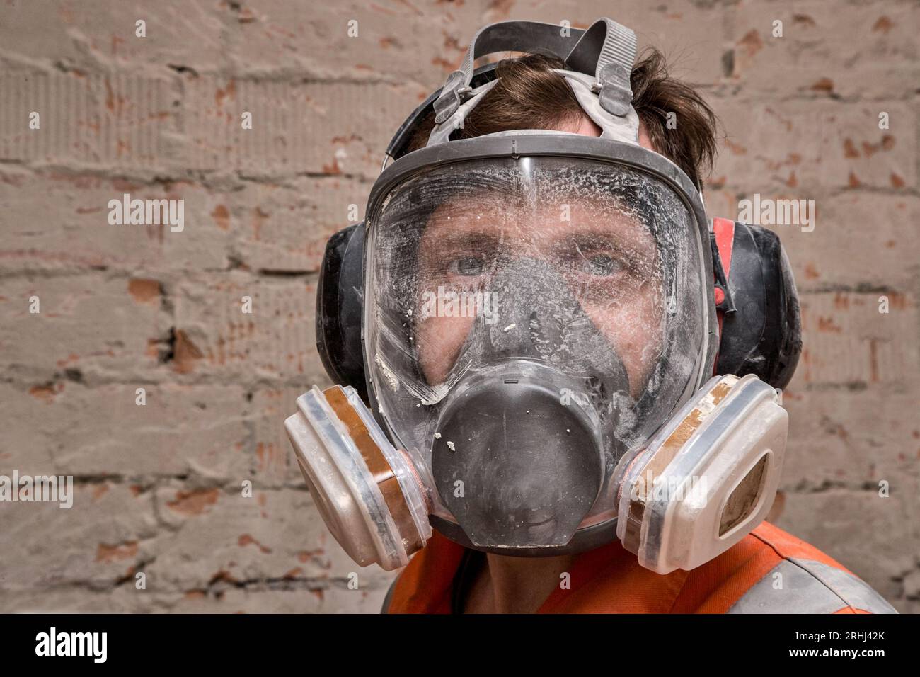 Männlicher Arbeiter, der Vollgesichts-Atemschutzmaske und Gehörschutz für Arbeiten in Gefahrenumgebungen trägt. Stockfoto