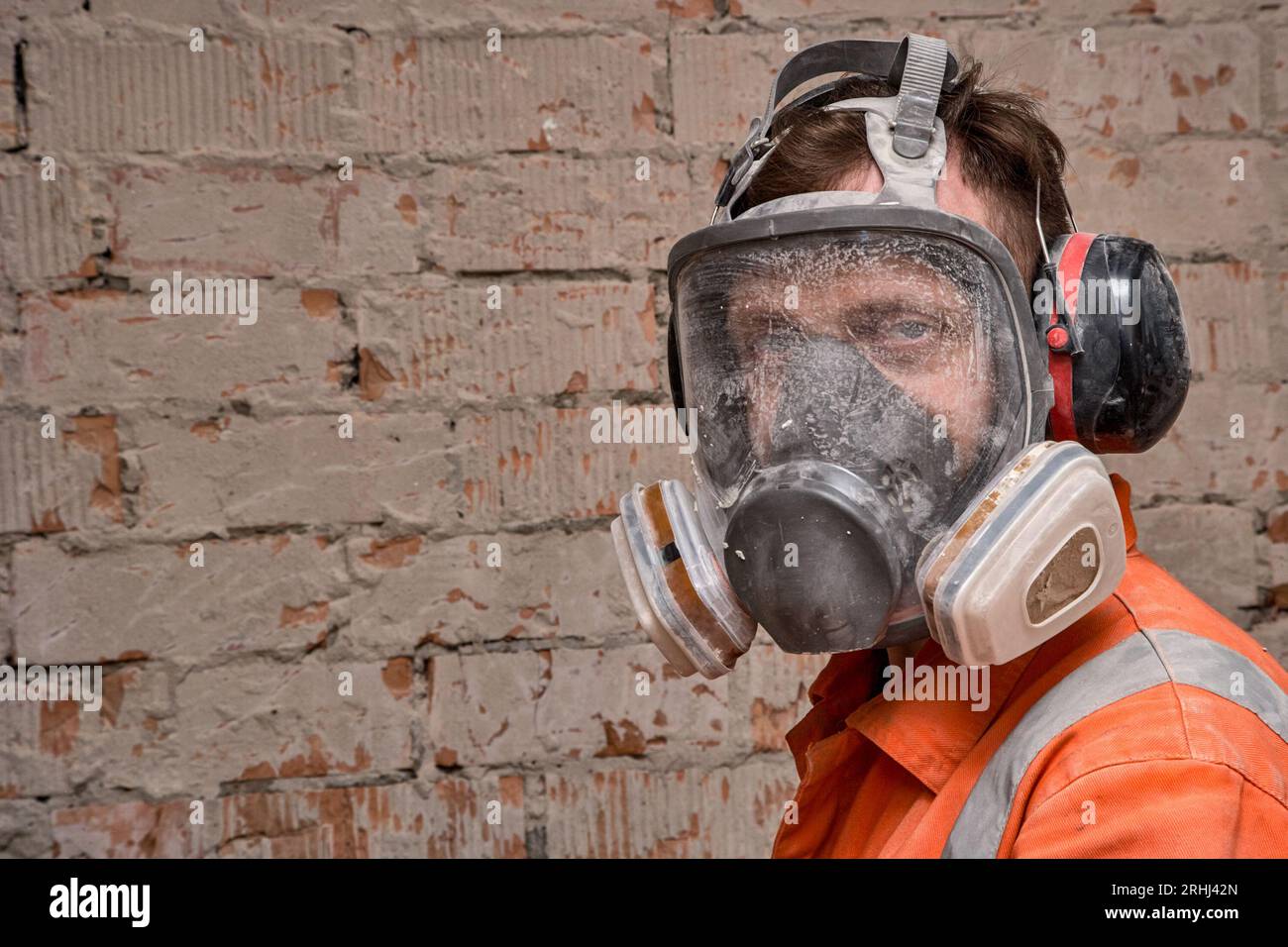 Bauarbeiter, der Vollmaske und Gehörschutz für Arbeiten in Gefahrenumgebungen trägt. Stockfoto