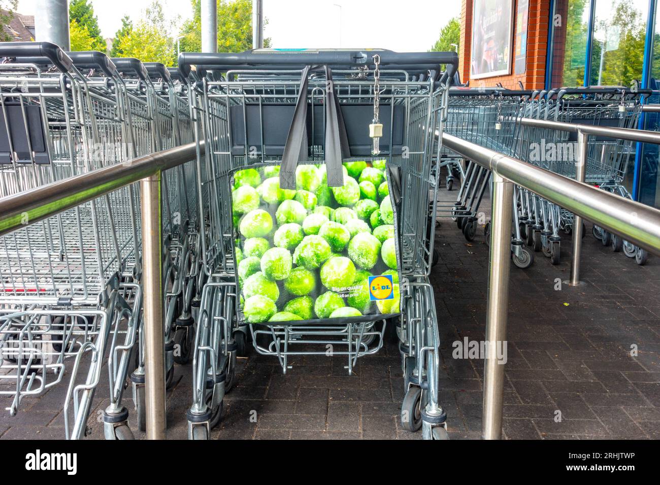 Eine Person hat ihre Lidl-Einkaufstasche auf der Rückseite eines Trolleys vor einem Lidl-Supermarkt hängen gelassen. Stockfoto