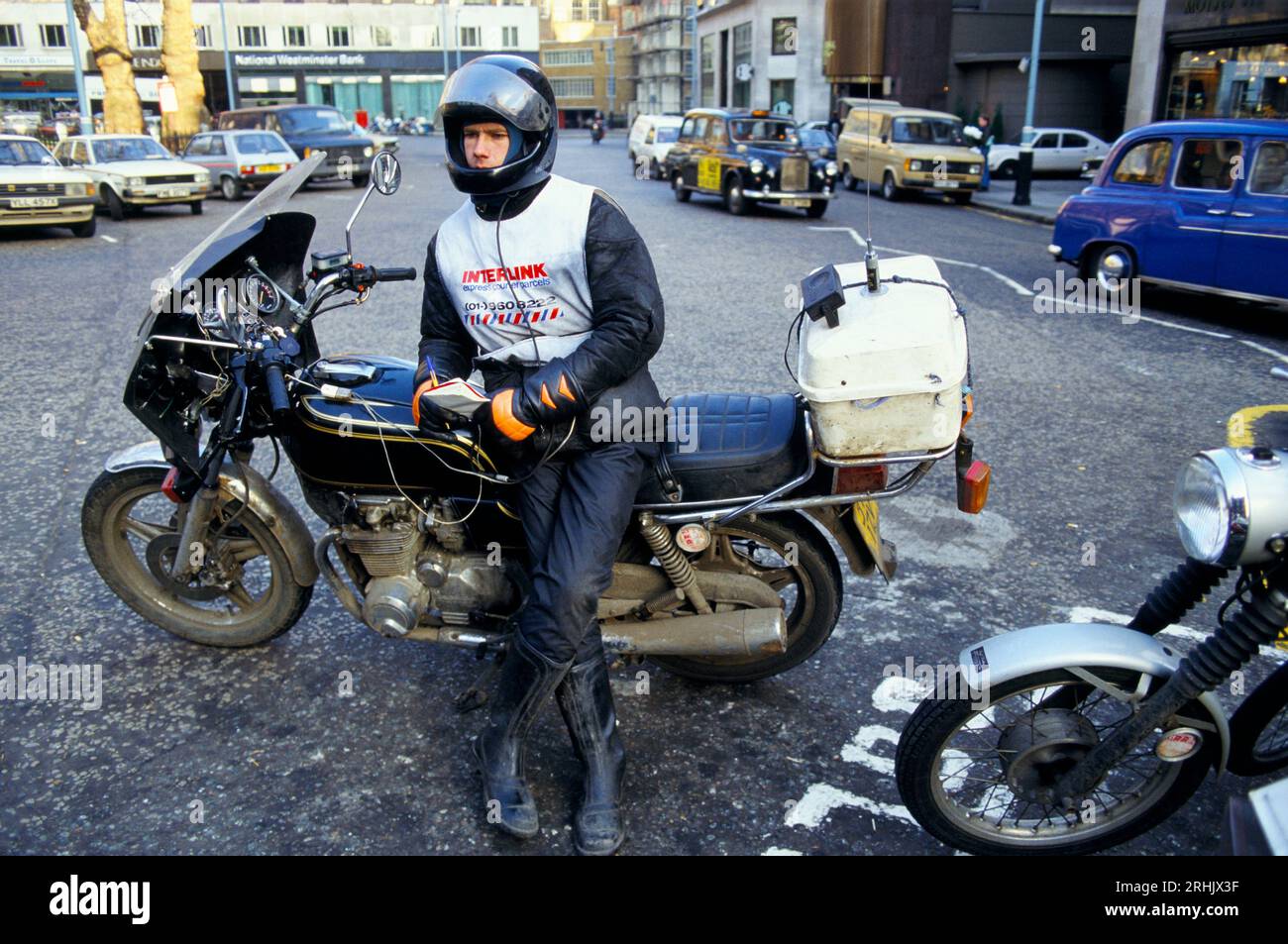 Motorrad Courier Dispatch Rider 1990s trägt wasserdichte Schutzkleidung Central London Berkley Square und wartet darauf, dass ihm ein Job zugestellt wird. UK. Um 1995. HOMER SYKES Stockfoto