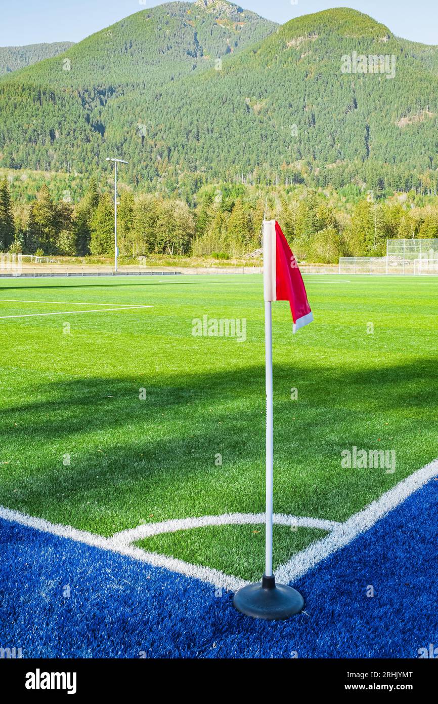 Eine rote Flagge an einer Ecke des Fußballstadions und an der Fußballecke eines Fußballplatzes. Eckfahne auf grünem Kunstrasen. Leeres Fußballfeld g Stockfoto