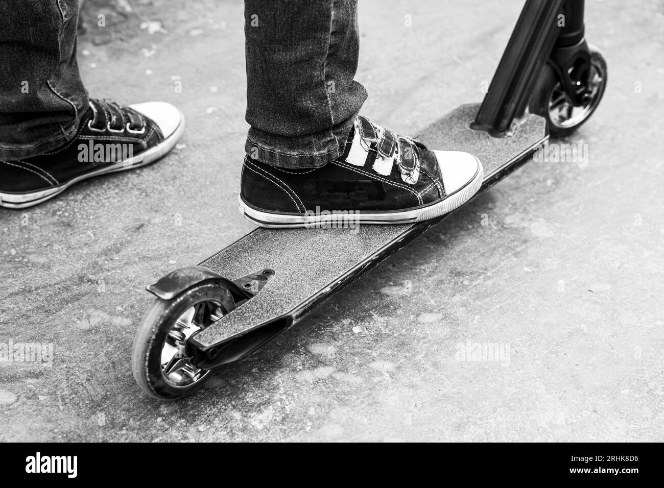 Ein Junge auf einem Roller in einem Skatepark spielt Sprünge und Tricks. Extrem städtischer Outdoor-Sport, gesundes Lifestyle-Konzept. Sportliche Freizeitangebote. Schwarz auf Weiß Stockfoto