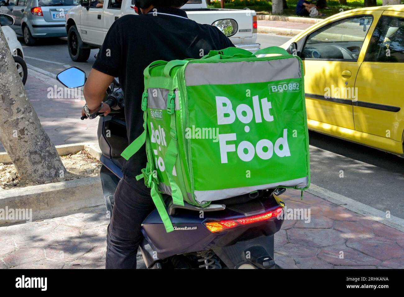 Gozo, Malta - 5. August 2023: Person, die einen Motorroller mit einem isolierten Container für den Bolt Food-Lieferservice auf der Rückseite fährt Stockfoto