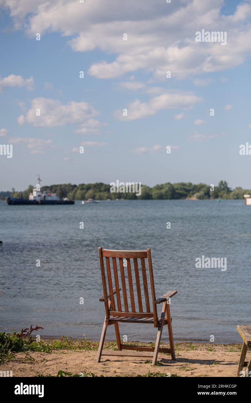 Ein leerer Holzstuhl am Strand mit Blick auf den Lake Ontario steht für einen erholsamen Urlaub in einem Ferienhaus und ein Gleichgewicht zwischen Berufs- und Privatleben Stockfoto