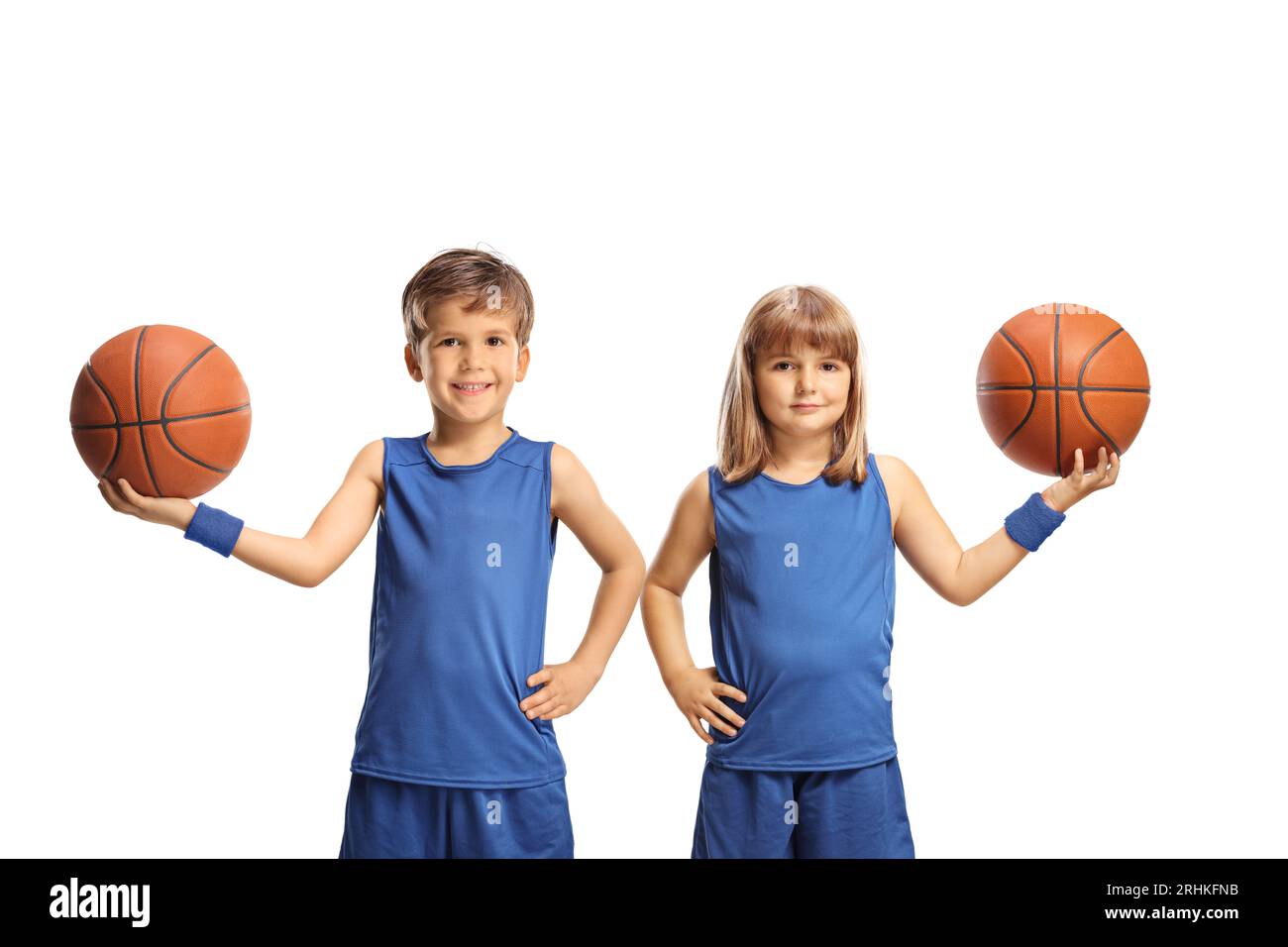 Junge und Mädchen in blauen Sportrikots, die Basketbälle halten und die Kamera auf weißem Hintergrund lächeln Stockfoto