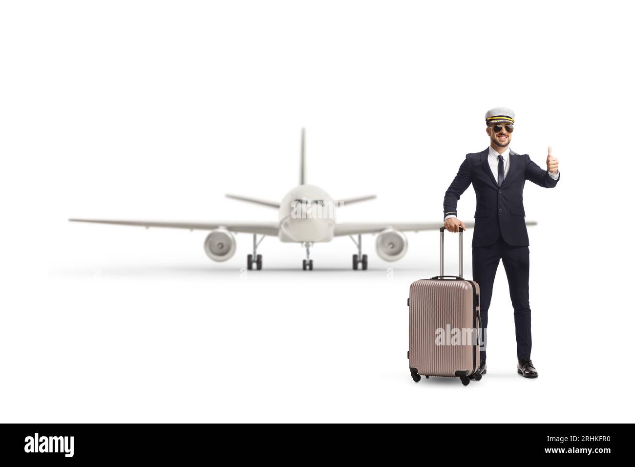Portrait eines jungen Piloten in voller Länge mit einem Koffer, der ein Daumen-nach-oben-Zeichen vor einem Flugzeug auf weißem Hintergrund zeigt Stockfoto