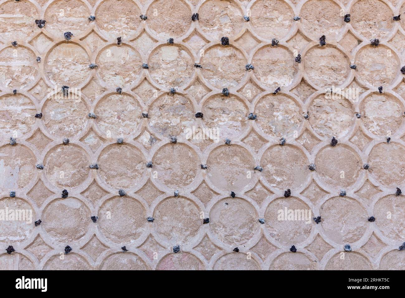 Dekorative Steinfassade des Alcazar von Segovia, Spanien. Islamische Ornamente mit kreisförmigen Sgraffito-Motiven, geschnitzte Kreise an Steinwänden. Stockfoto