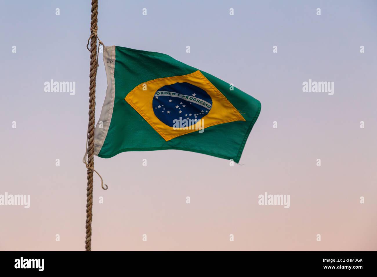 brasilianische Flagge im Freien mit einem wunderschönen farbenfrohen Sonnenuntergang am Himmel von Rio de Janeiro. Stockfoto
