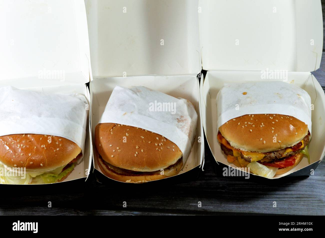 Haufen Sesambrötchen mit frittierten panierten Hähnchenfilet-Pattys, knackigem Salat, Schmelzkäse, Zwiebeln und Sauce, saftigem, dickem, doppeltem Rinderpatty mit Chees Stockfoto