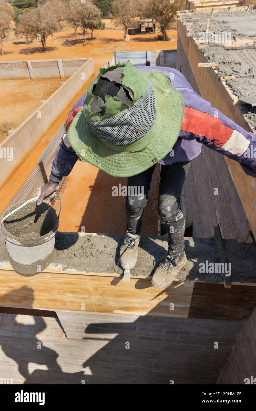 Betongießen auf der obersten Etage afrikanische Arbeiter balancieren am Rand mit einem Eimer Gießen Beton auf der obersten Etage afrikanische Arbeiter balancieren auf der Stockfoto