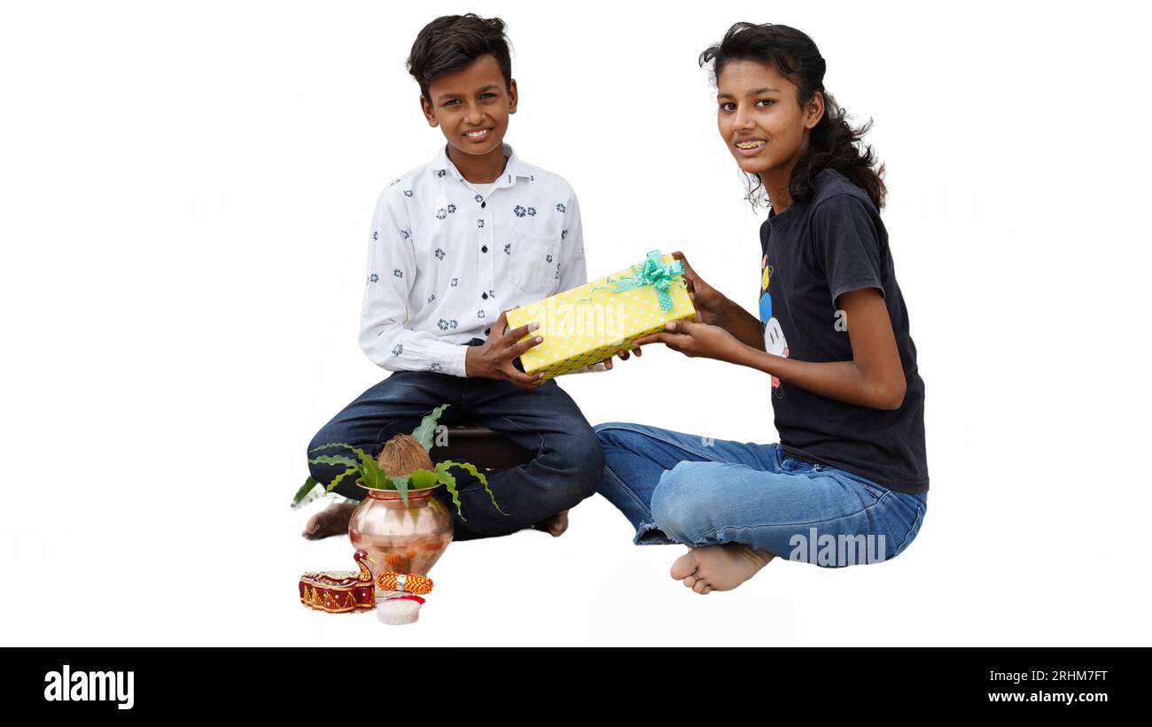 Die indische Schwester bindet Rakhi an das Handgelenk ihres kleinen Bruders und tauscht Geschenke und Süßigkeiten auf dem Raksha Bandhan oder Bhai Dooj Festival aus Stockfoto