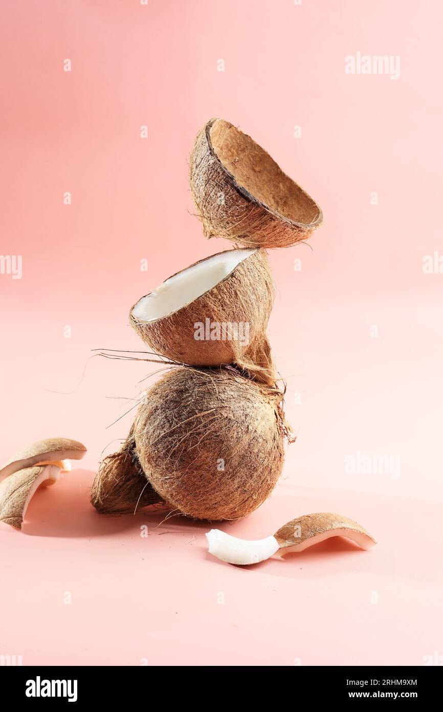 Gestapeltes Kokosfleisch und Kokosnussschale auf rosafarbenem Hintergrund, Konzept natürliche reife Kokosnuss. Bereich für Text kopieren Stockfoto