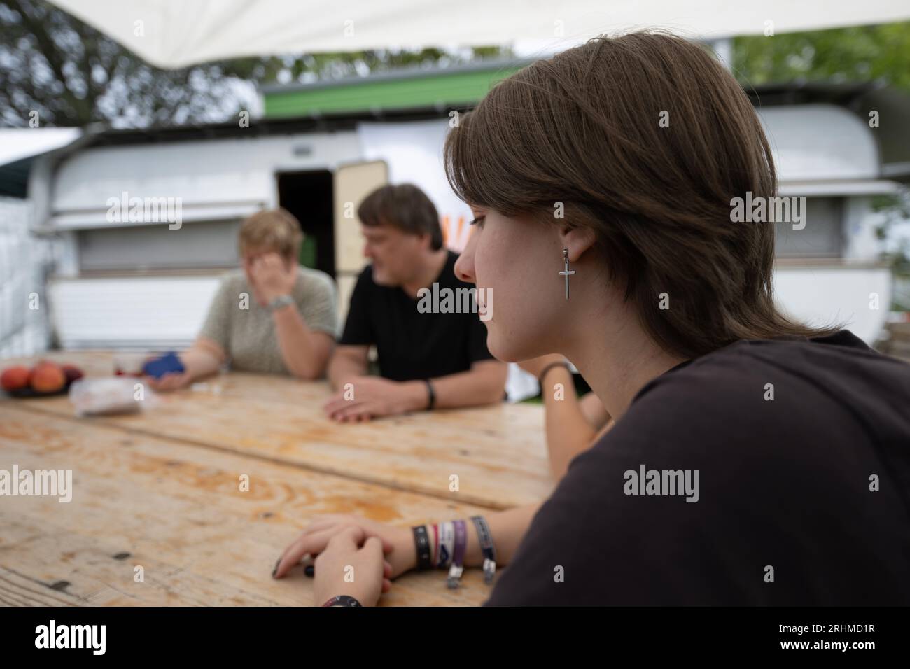 St. Leon Rot, Deutschland. August 2023. Josi, ein Mitarbeiter der Campingkirche, sitzt an einem Biertisch auf einem Grundstück auf dem Campingplatz am Lake St. Leon. Die Evangelische Kirche in Baden-Württemberg organisiert zwölf Campingkirchen im Land. Sie nutzen die Freizeit der Menschen im Urlaub, um ihr Interesse an Glauben zu wecken und mit ihnen darüber ins Gespräch zu kommen. (An dpa 'Kinder als 'Türöffner' zum Glauben - Kirche auf dem Campingplatz') Kredit: Marijan Murat/dpa/Alamy Live News Stockfoto