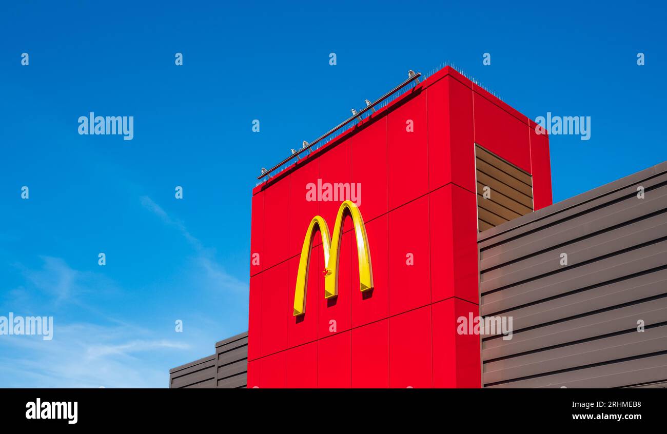 McDonald's beliebte goldene Bögen auf einem roten Schild mit blauem Himmel. Teil des roten Gebäudes mit dem Logo McDonalds in Vancouver Cana Stockfoto