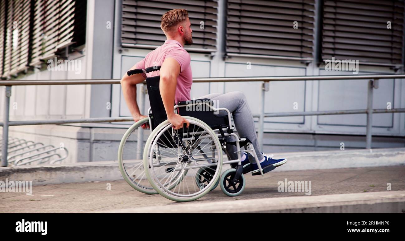 Mann Mit Körperlicher Behinderung Im Rollstuhl Auf Der Rampe Im Freien Stockfoto