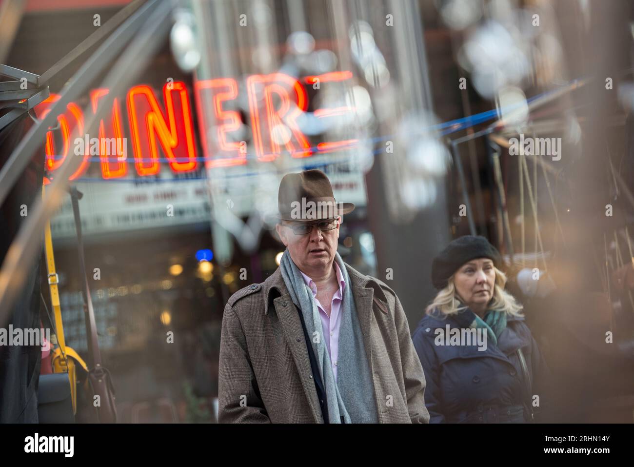 Stilvolle Paare gehen an einem Retro-Neon-Diner-Schild auf dem Spitalfields Market, East London vorbei, das sich an einem kühlen Wintertag in Glas spiegelt Stockfoto