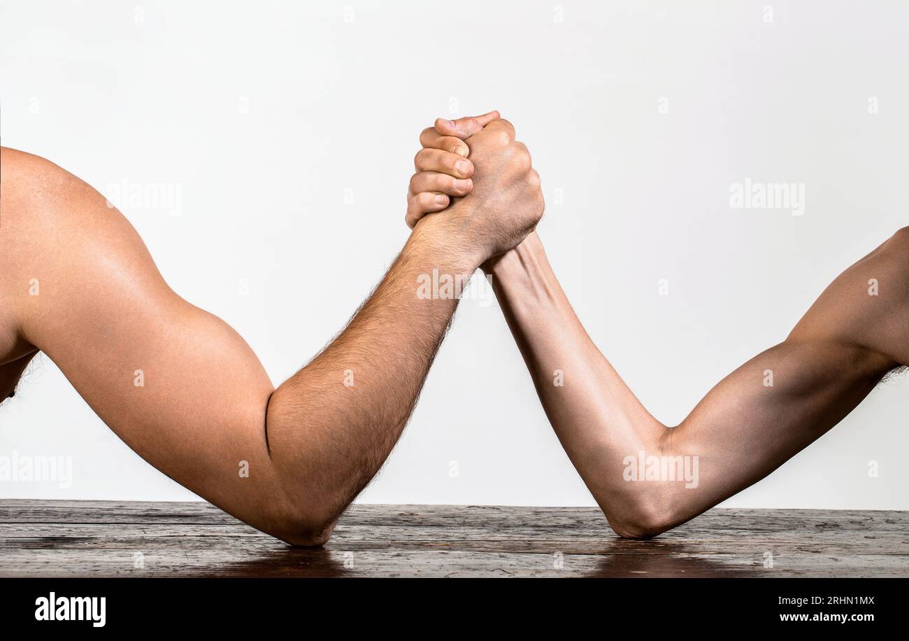 Schwer bemuskelter Mann Arm, der einen strapaziösen schwachen Mann wringt. Zwei Männer haben Armringen geschlossen, stark und schwach, ungleiche Übereinstimmung Stockfoto