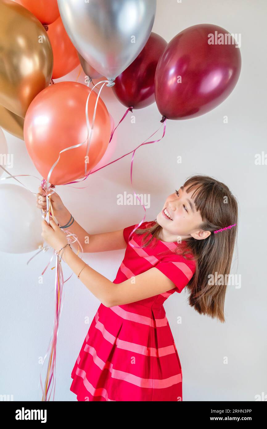 Ein zehnjähriges Mädchen, umgeben von Geburtstagsballons Stockfoto