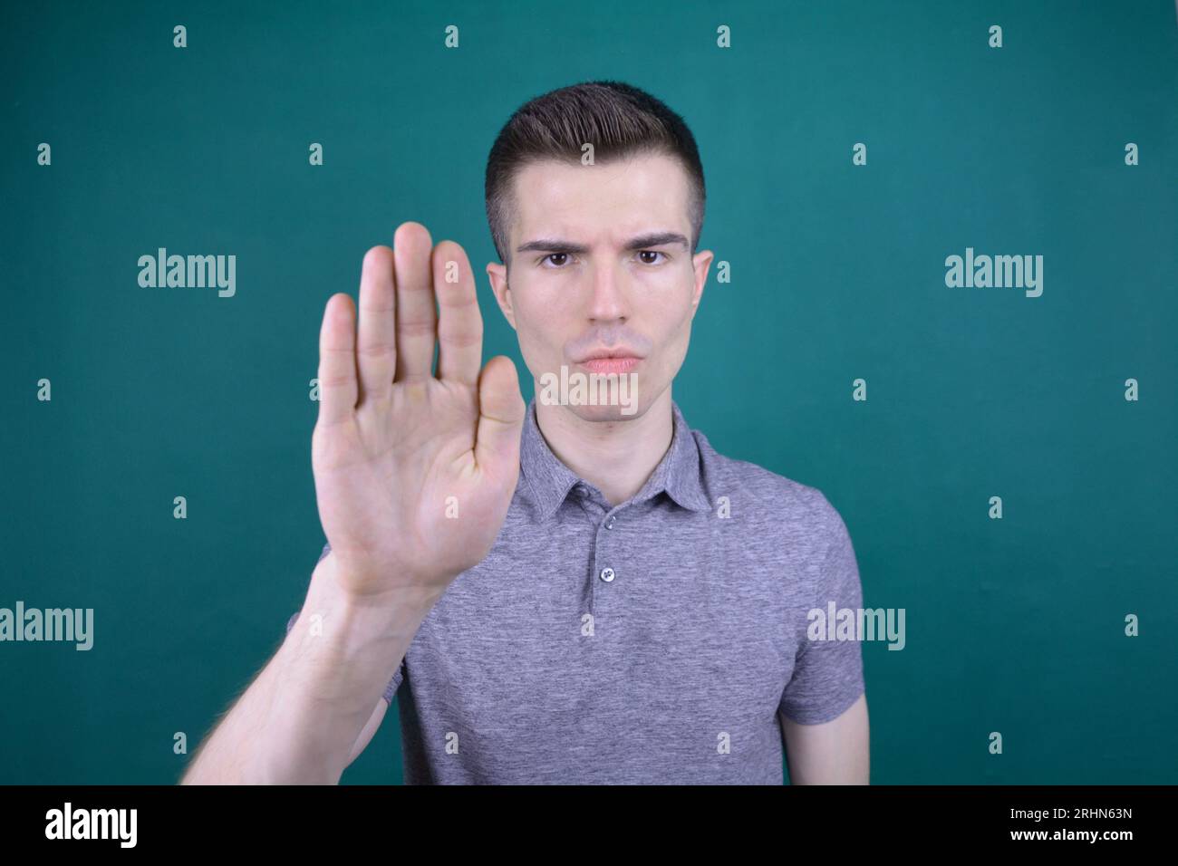 Seriöser junger Mann mit offener Hand in Stoppgeste auf isoliertem Hintergrund Stockfoto