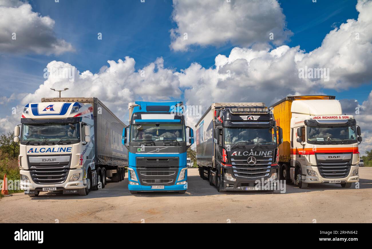 Vier kommerzielle knickgelenkte Lastkraftwagen oder Lkw mit einer Tragfähigkeit von jeweils bis zu 44 Tonnen, die in einer Linie am Lincoln Farm Truck Stop in Balsall geparkt sind Stockfoto