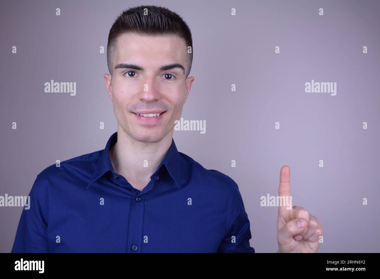 Elegant lächelnd gutaussehend junger Kaukasier zeigt mit dem Finger nach oben auf isolierten Hintergrund - Copy Space Stockfoto