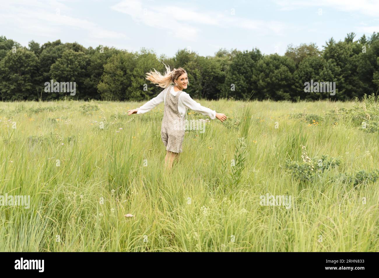 Eine Frau im Strampler, die auf einem Grasfeld tanzt Stockfoto