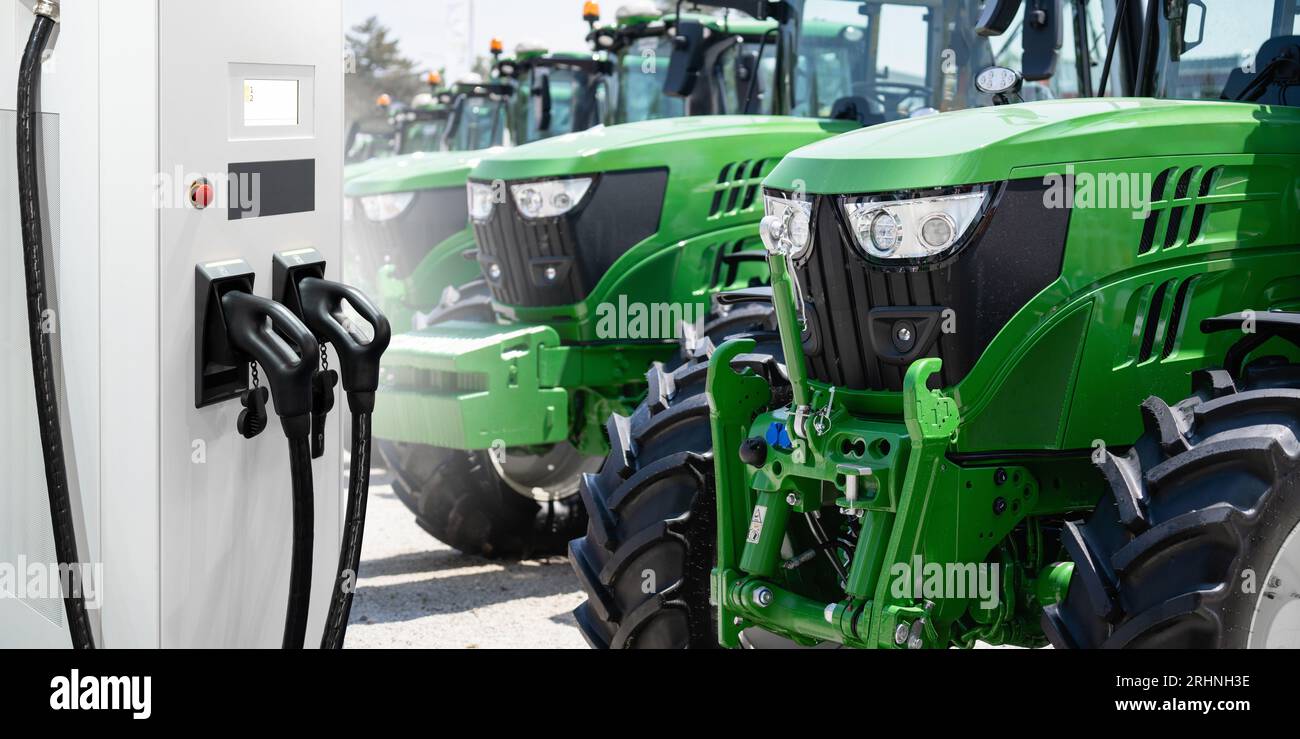 Ladestation für Elektrofahrzeuge auf einem Hintergrund von landwirtschaftlichen Traktoren. Konzept... Stockfoto