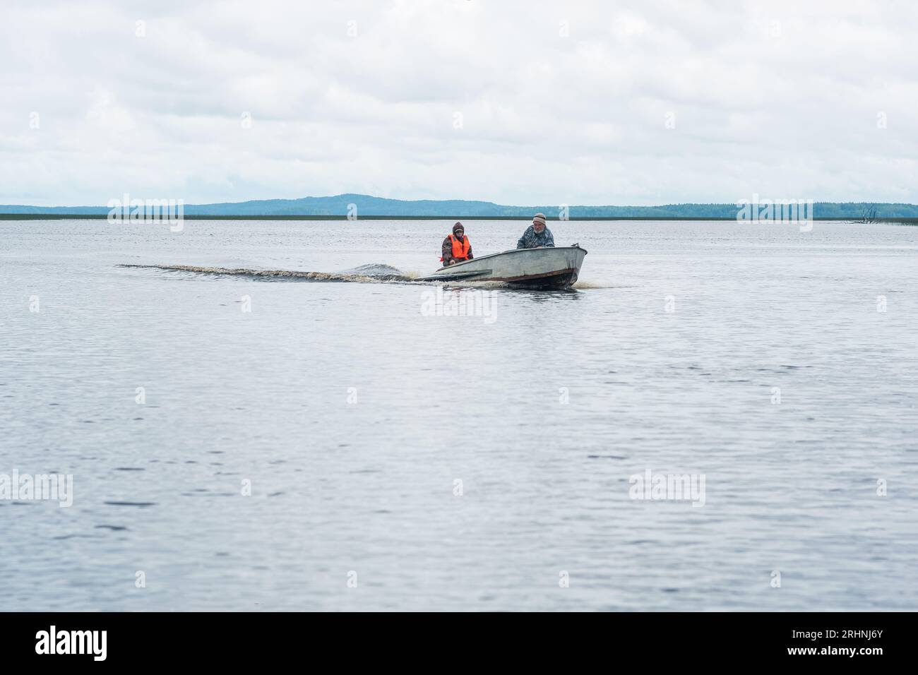 Karelien, Russland - 24. Juli 2023 - Fischer auf einer Motorbootfahrt über einen breiten See Stockfoto