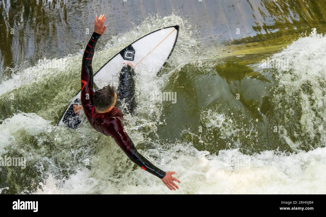 18. August 2023, Bayern, München: Ein Surfer fährt mit seinem Board auf der Surfwelle Floßlände nahe der Isar im Süden der bayerischen Hauptstadt. Foto: Peter Kneffel/dpa Stockfoto