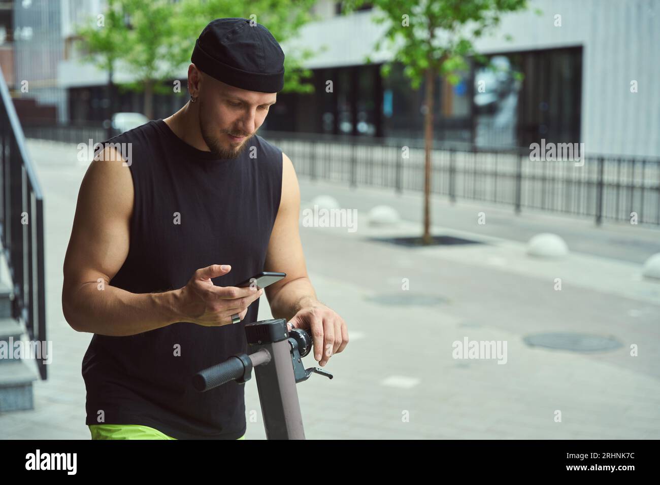 Junger Stadtmensch mit Roller und Telefon auf der Straße Stockfoto
