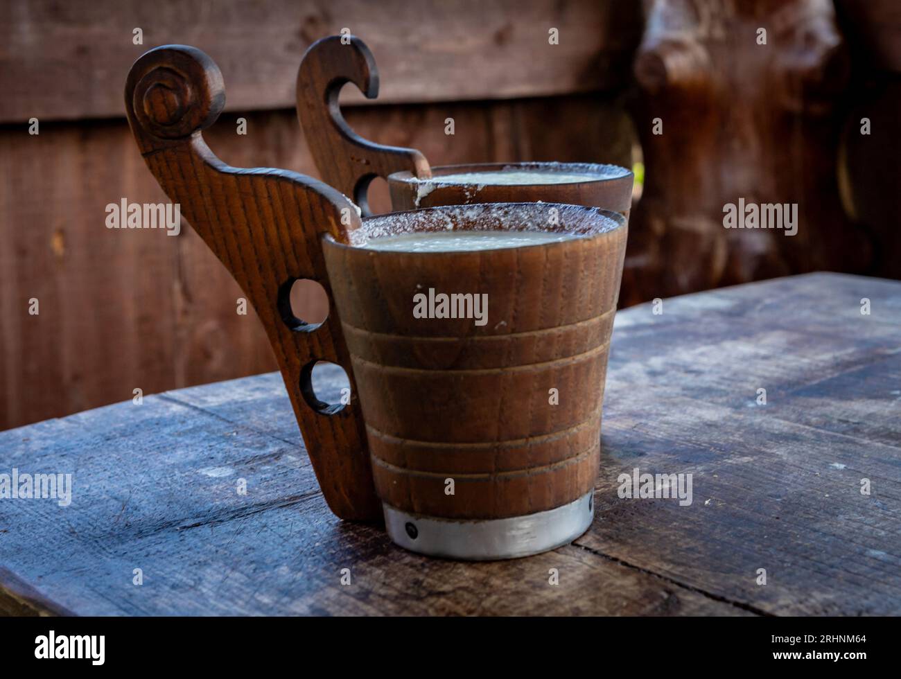 Zwei Holztassen mit fermentierter Schafmilch auf dem Tisch. Hirtenhütte in Pieniny, Polen. Stockfoto