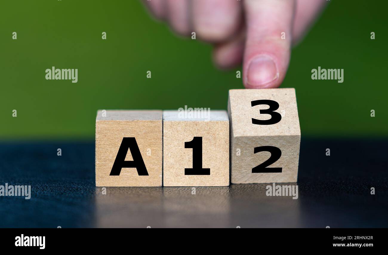 Symbol für eine Lohnerhöhung in Deutschland. Hand dreht Holzwürfel und ändert die deutsche Gehaltsstufe von A12 auf A13. Stockfoto