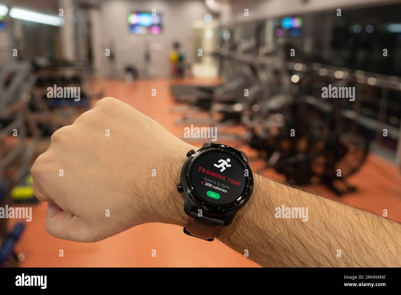 Ein Mann bereitet sich darauf vor, auf einem Laufband zu beginnen. Smart Watch auf der Hand des Athleten. Anwendungen für Smartwatch für Outdoor-Training. Muskeltraining Stockfoto