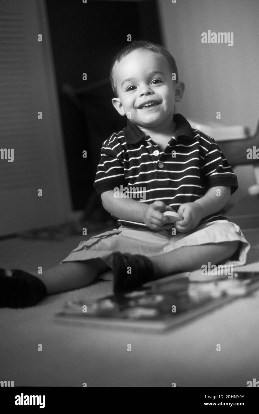 Junge, der auf dem Boden sitzt und in seinem Zimmer spielt Stockfoto